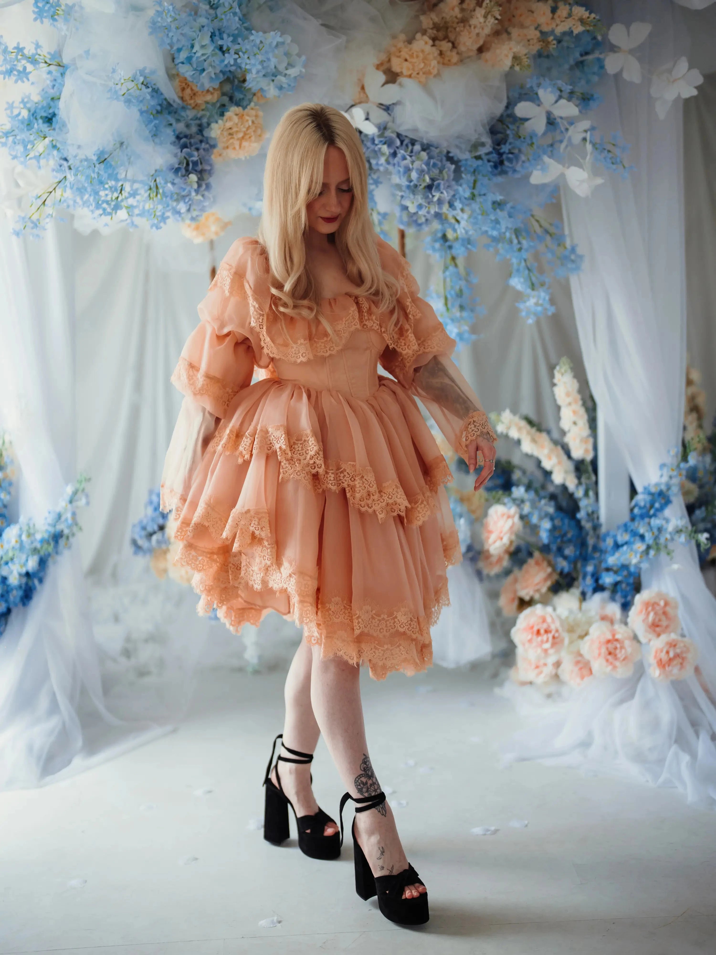 Model wearing the Midnight Symphony Organza Mini Dress in a floral setting, emphasizing its fairy tale-inspired silhouette and romantic lace details.
