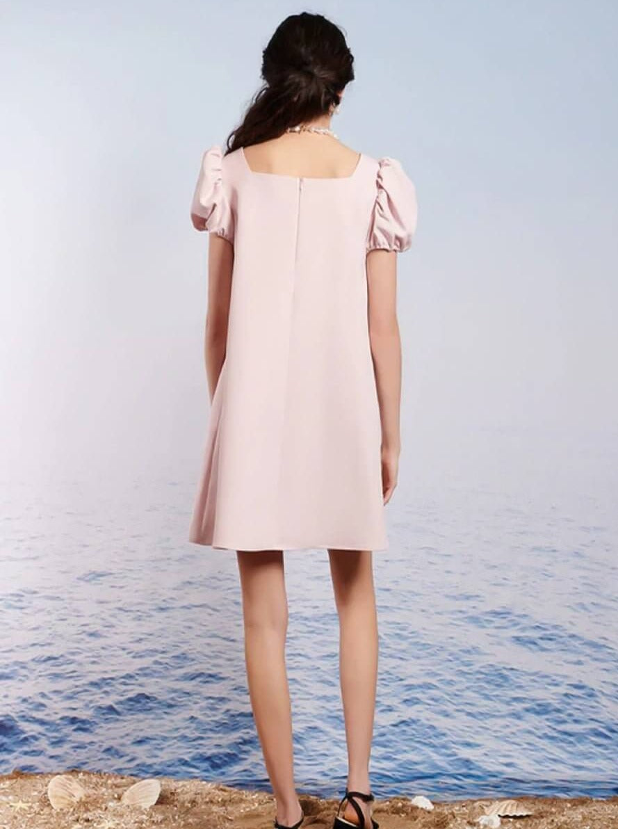 Person wearing a Pale Pink Paddle Bow Mini Dress with puffed shoulders, facing away