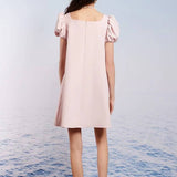 Person wearing a Pale Pink Paddle Bow Mini Dress with puffed shoulders, facing away