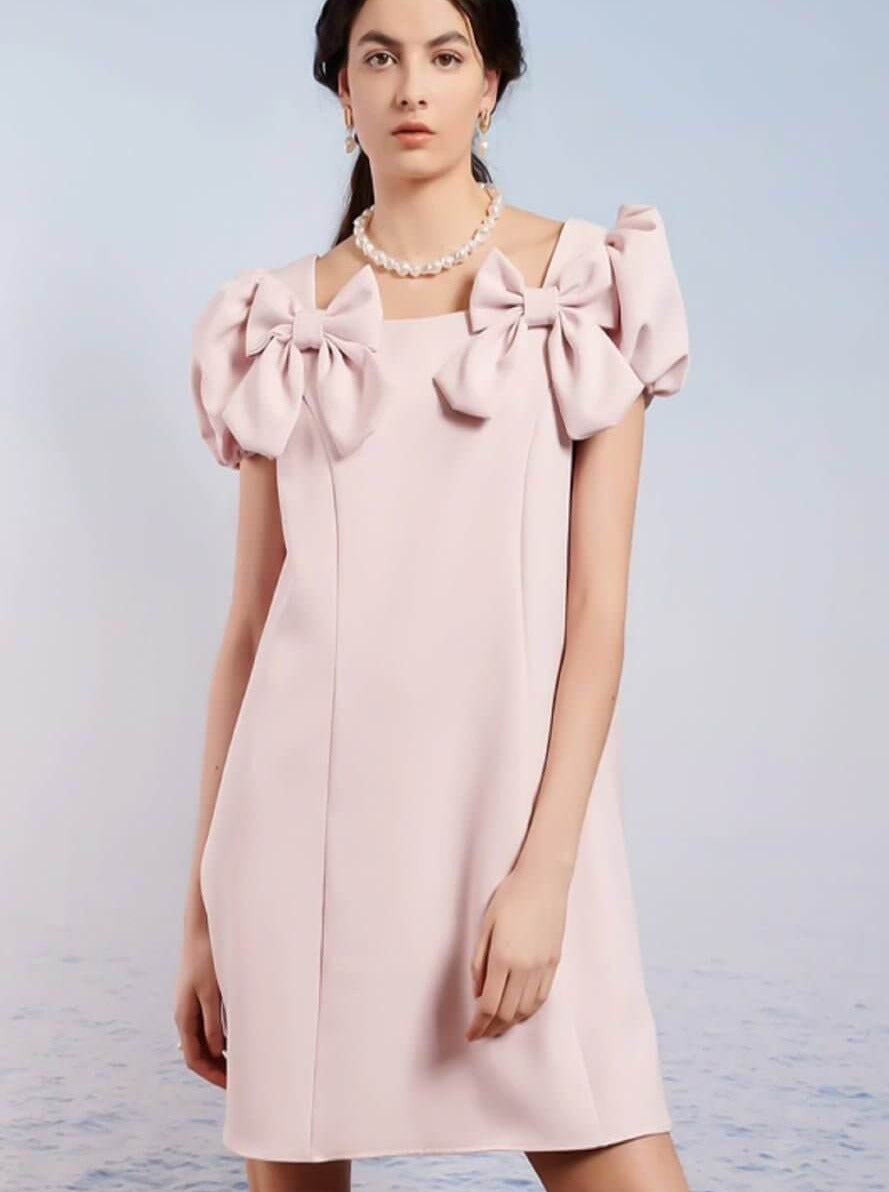 Paddle Bow Mini Dress featuring a pale pink color and bow-adorned puff sleeves