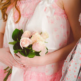 Pink floral dress from the Parfait Poet Selkie Collection, holding a small bouquet of roses