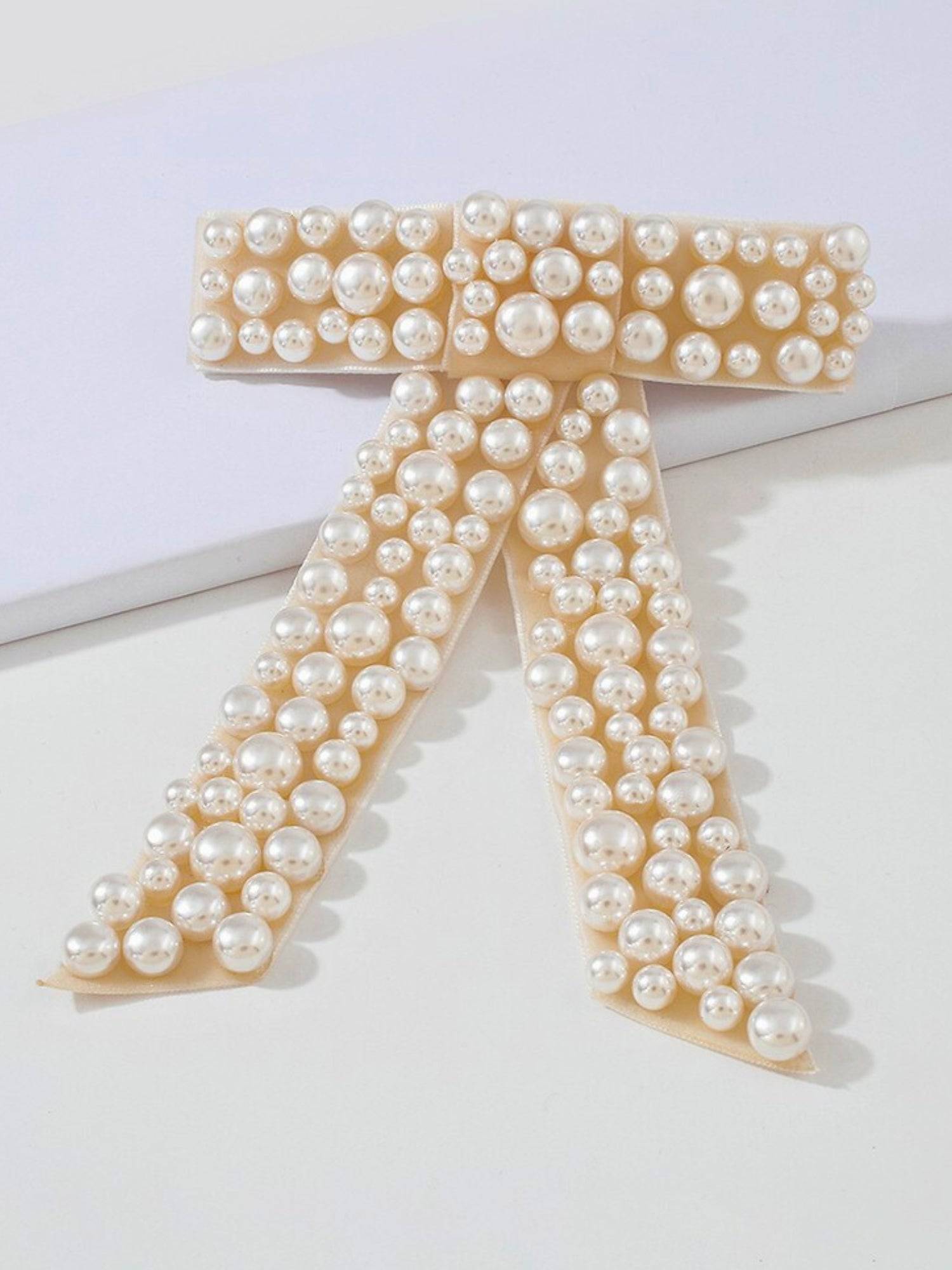 The Pearl Bow Hair Barrette featuring a stunning pearl-encrusted bow-shaped design.