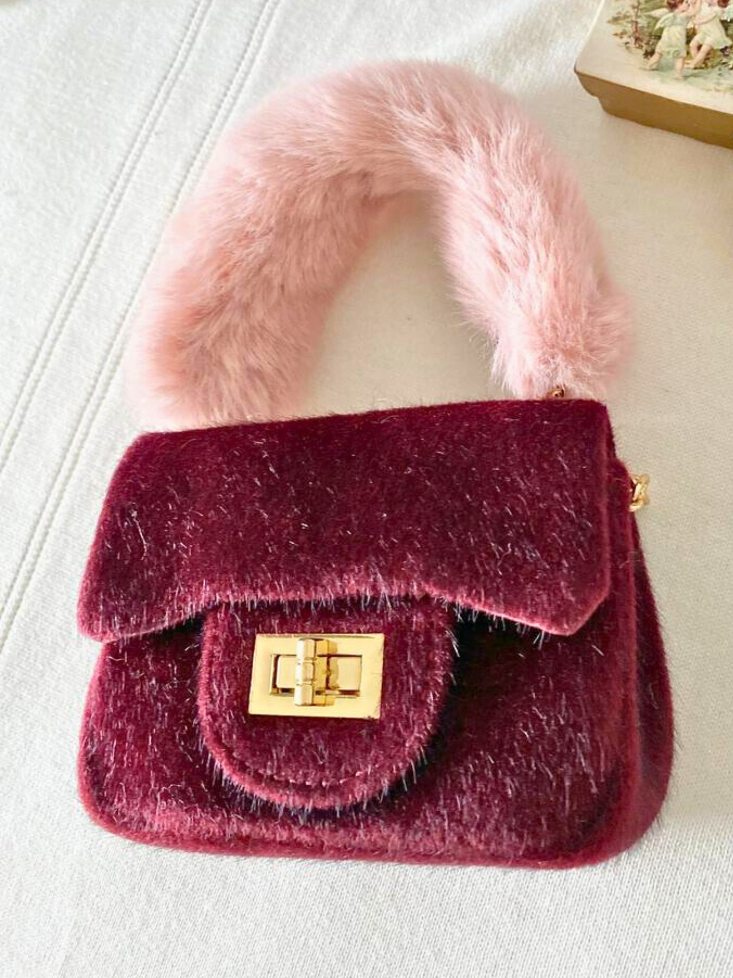 Burgundy Petit Agneau Micro Handbag with pink faux fur handle and gold clasp