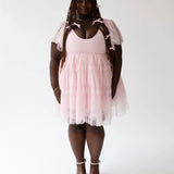 Woman with dreadlocks in a Pink Candy Cherub Dress featuring a fitted bodice and flared skirt