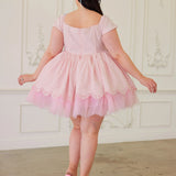 Back view of a woman wearing a pink cotton mini dress with lace details in a room with white ornate walls.