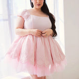 Front view of a woman wearing a pink cotton mini dress by a window.