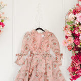 Pink floral Rapunzel Organza Marie Dress with long sleeves hanging on a wall