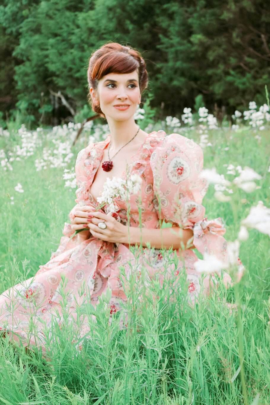 Woman in a pink floral dress in a field showcasing the Rapunzel Organza Marie Dress