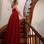 A woman in a red lace dress standing on a wooden staircase