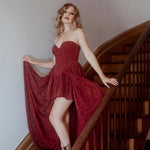 A woman in a red lace dress standing on a staircase