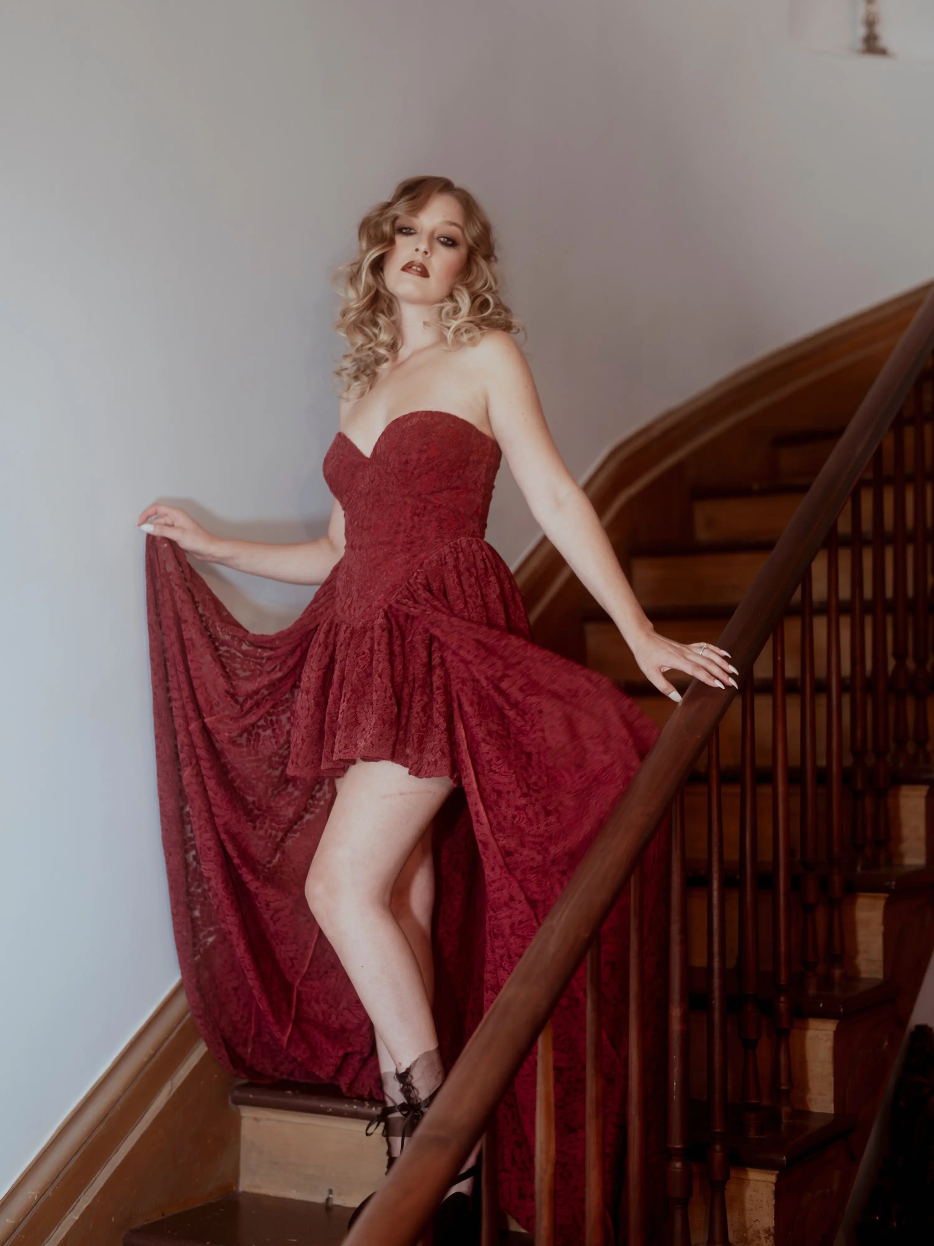 A woman in a red lace dress standing on a staircase