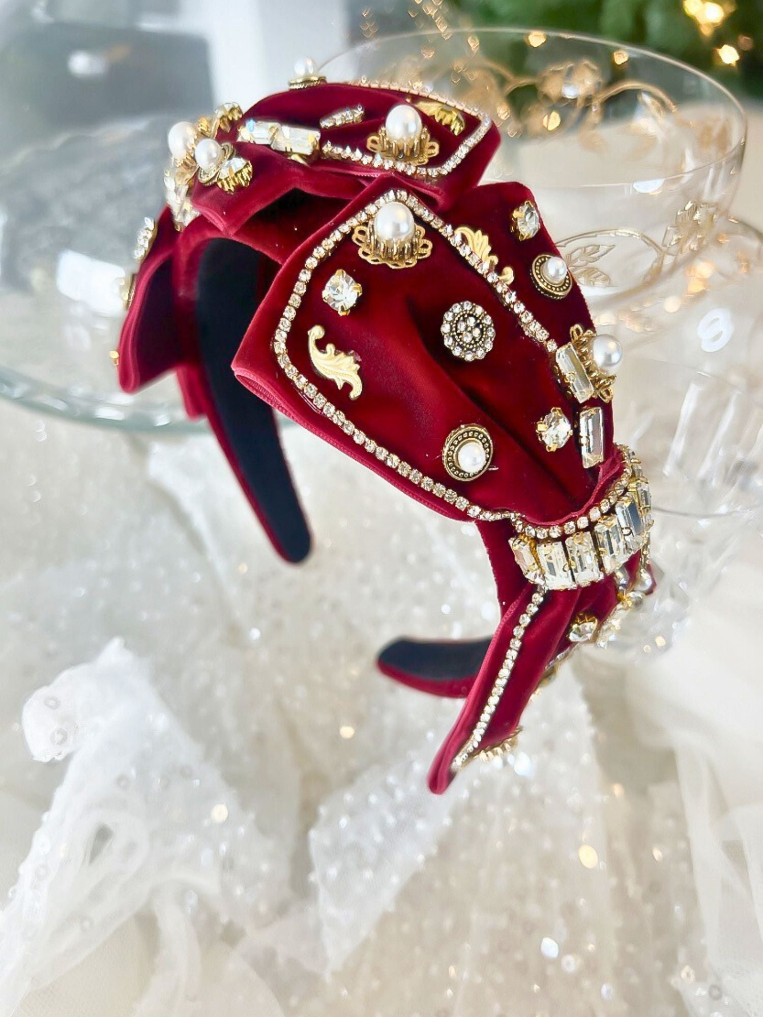 The Little Bit of Blair Red Velvet Headband features rich red velvet adorned with gold accents, pearls, and crystals for a luxurious hair accessory.