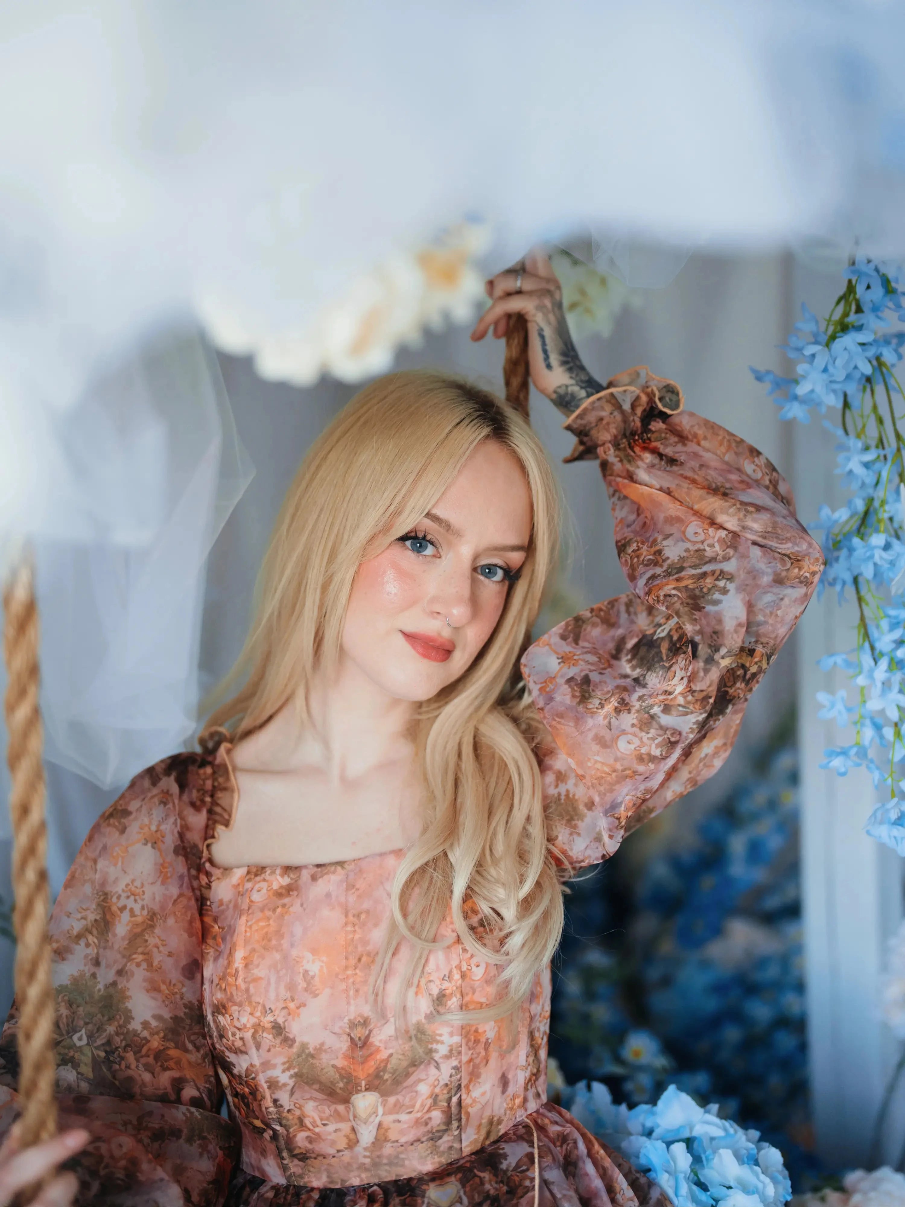 Portrait of a woman wearing a long sleeve ball gown highlighting the soft baroque print in a floral setting.