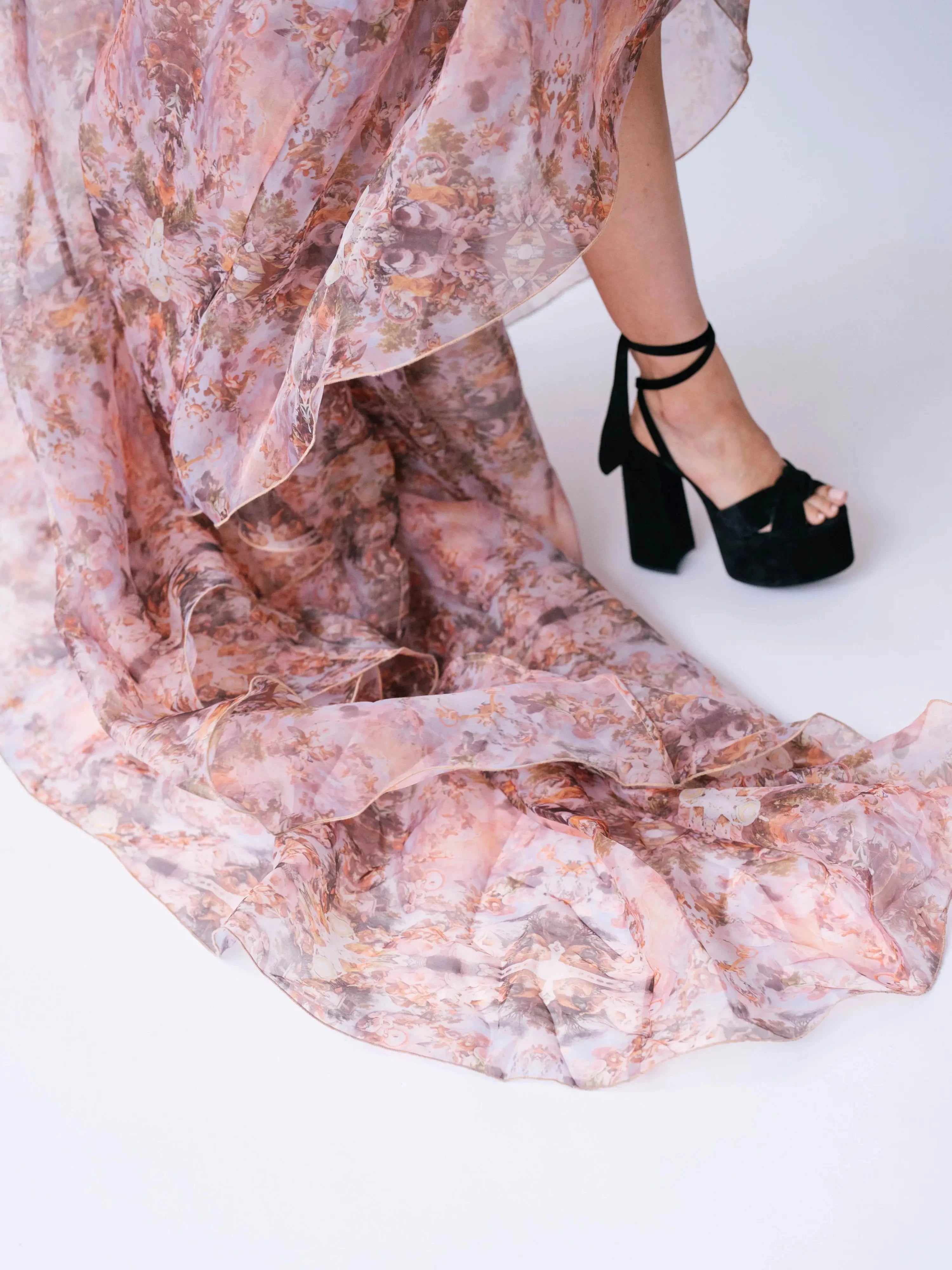 Close-up of the Ode to Jove Twilight Reverie Ball Gown's flowing organza train and baroque print, paired with black platform heels.