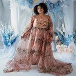 Plus-size model in the Ode to Jove Twilight Reverie Ball Gown with dramatic train and floral print, styled in a garden-inspired setting.