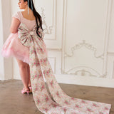 Ornate gown featuring a long floral train and a rosewater pink skirt with grand bow