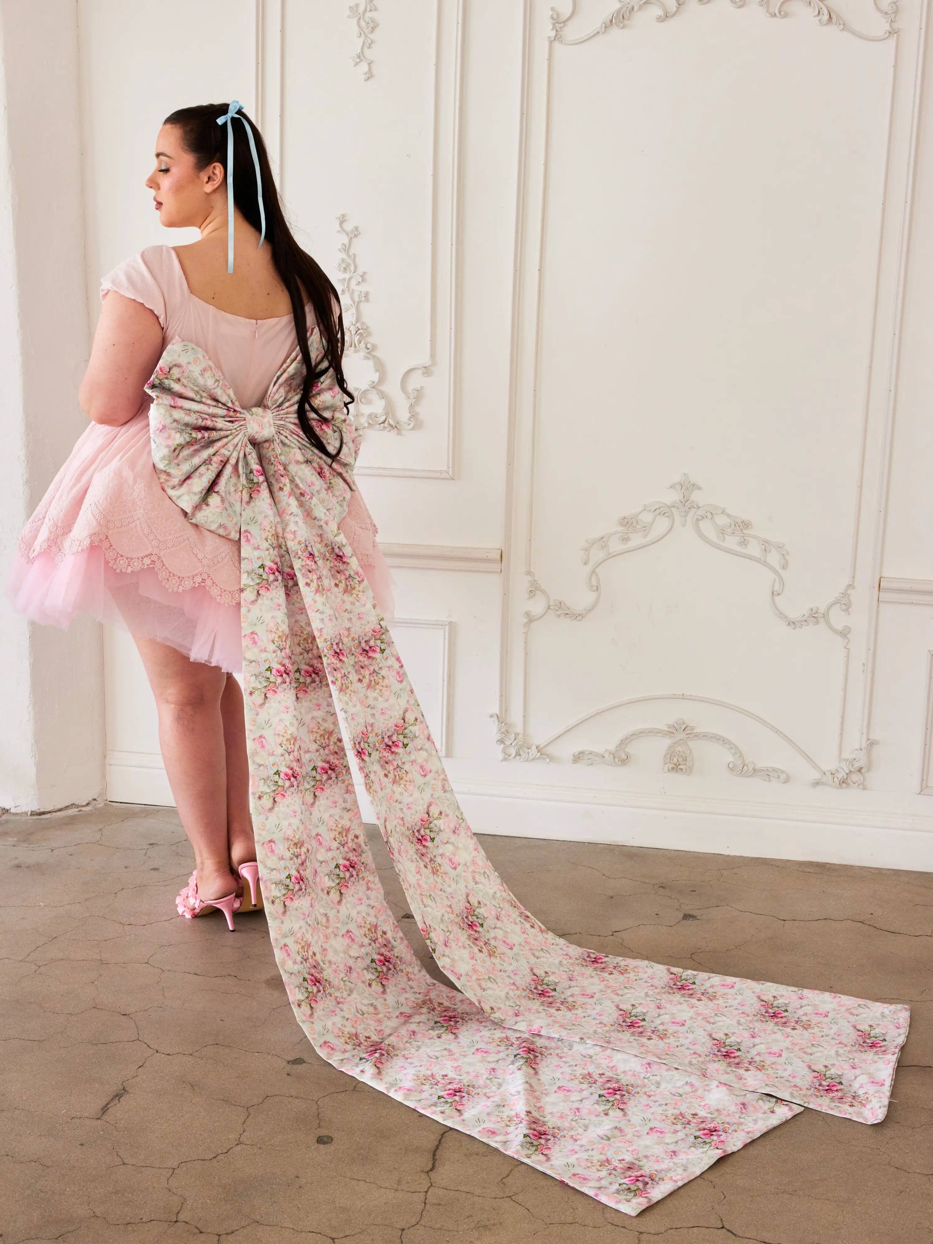 Ornate gown featuring a long floral train and a rosewater pink skirt with grand bow