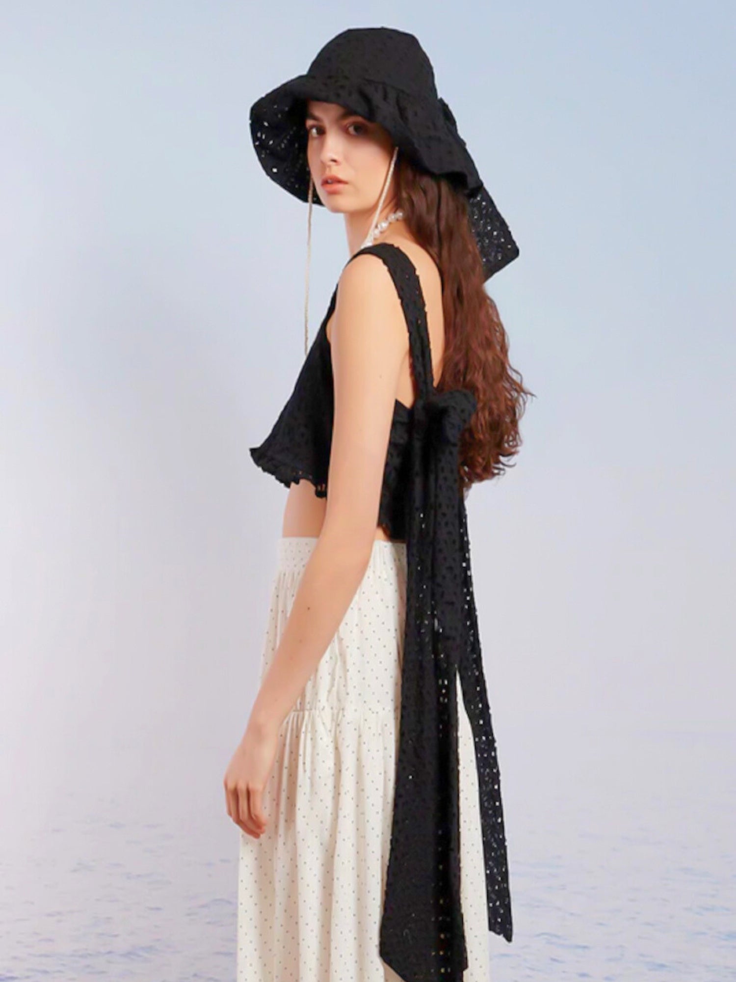 Woman in a black hat and white dress showcasing the Sand Castles Bow Blouse Top