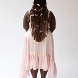 Woman with long braids in a pale pink Satin Ballet Midi Gown seen from behind