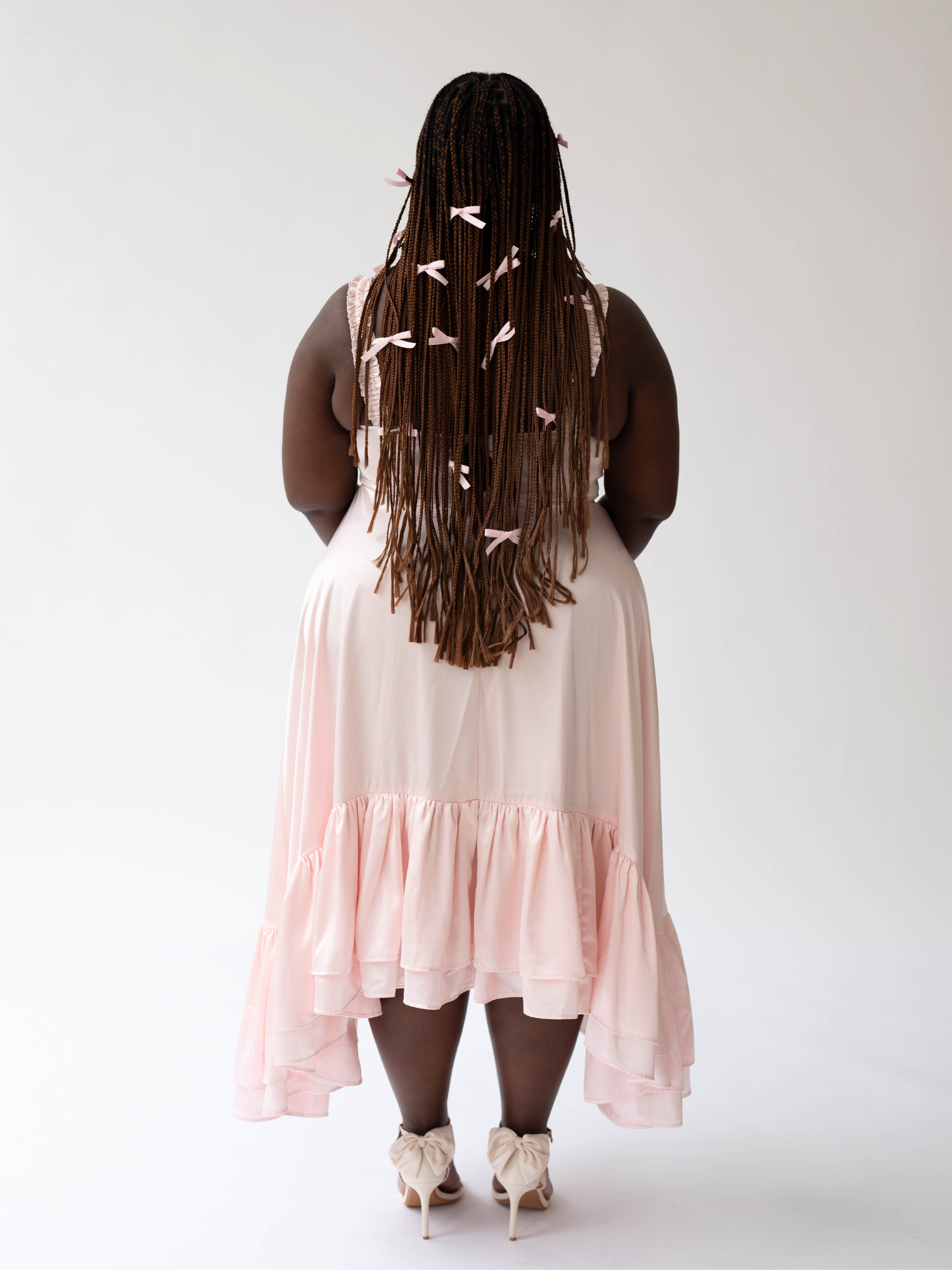 Woman with long braids in a pale pink Satin Ballet Midi Gown seen from behind