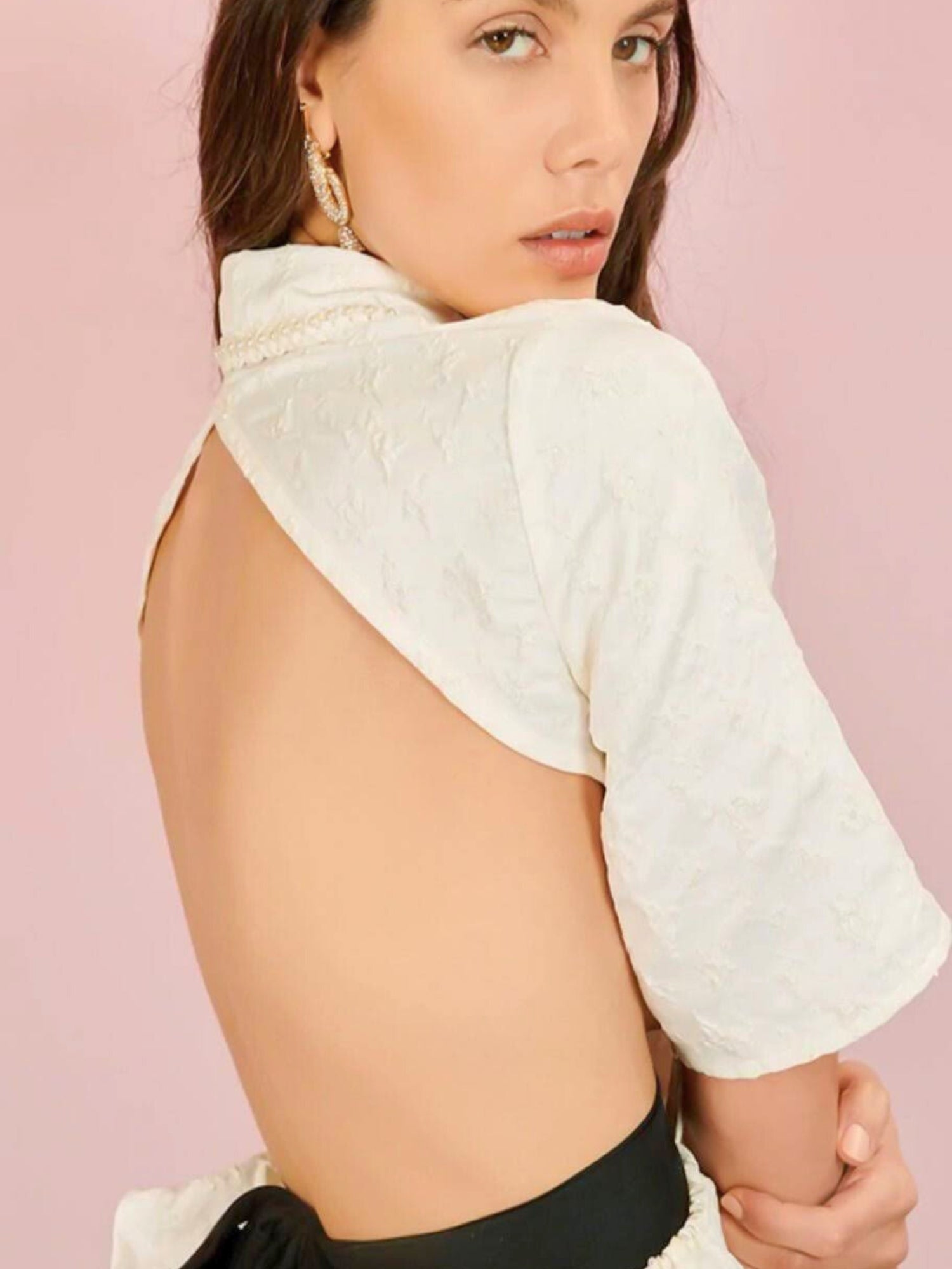 Woman in Seashore Cropped Blouse with grand bow sash against a pink background