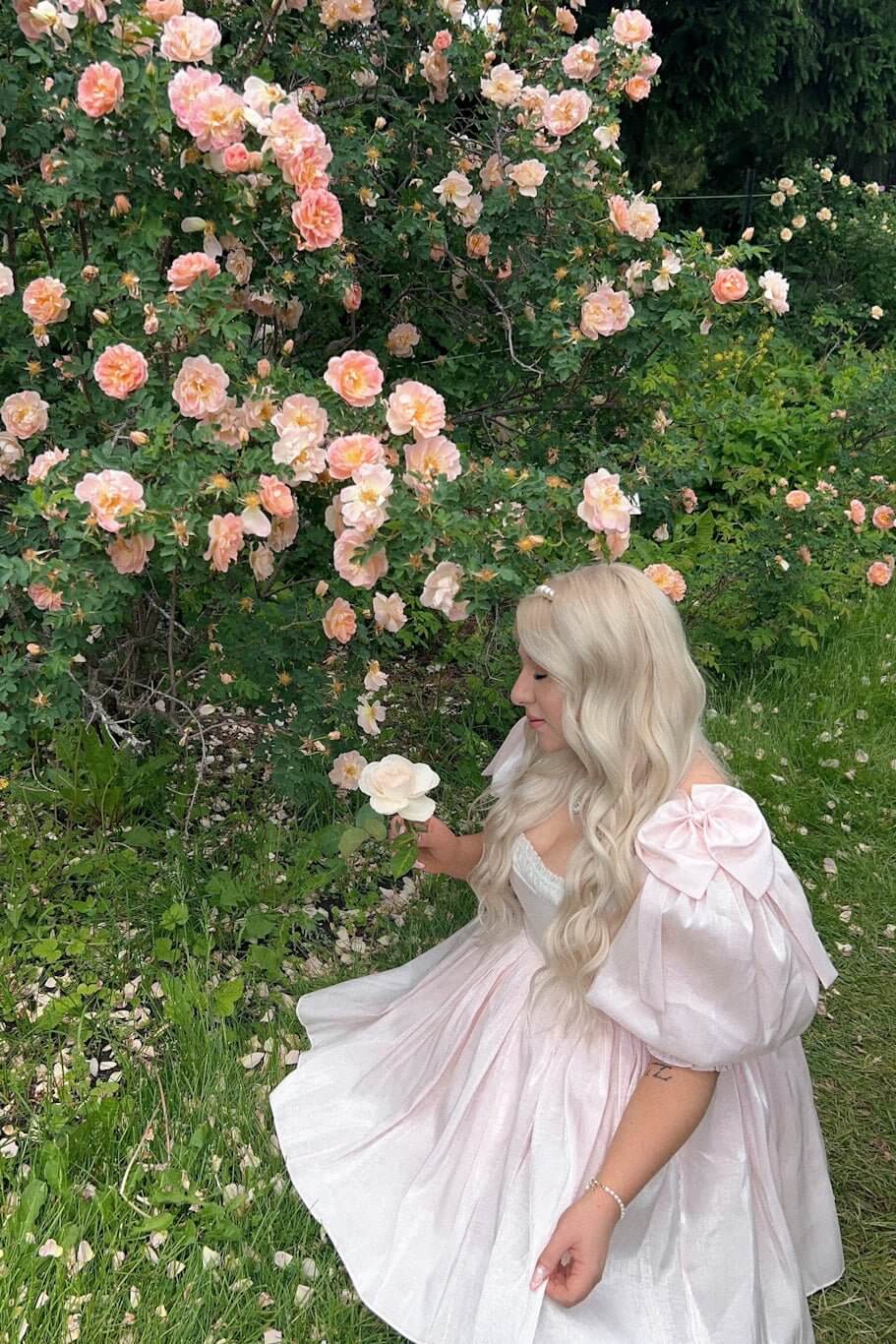 Blooming rose bush with pink flowers beside a Silk Peach Da Vinci Puff Dress