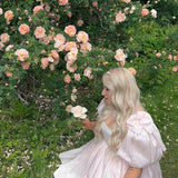 Blooming rose bush with pink flowers beside a Silk Peach Da Vinci Puff Dress