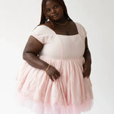 Woman in a Soft Pink Blossom Dress featuring a white bodice and tulle skirt