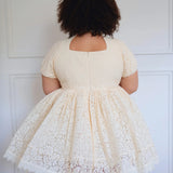 Back view of plus-size model in The Victorian Lace Tea Party Mini Dress showing full lace skirt and short puff sleeves.