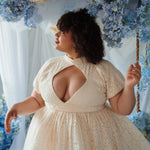 Plus-size model wearing The Victorian Lace Tea Party Mini Dress with diamond keyhole bust and high waist, surrounded by pastel hydrangeas.