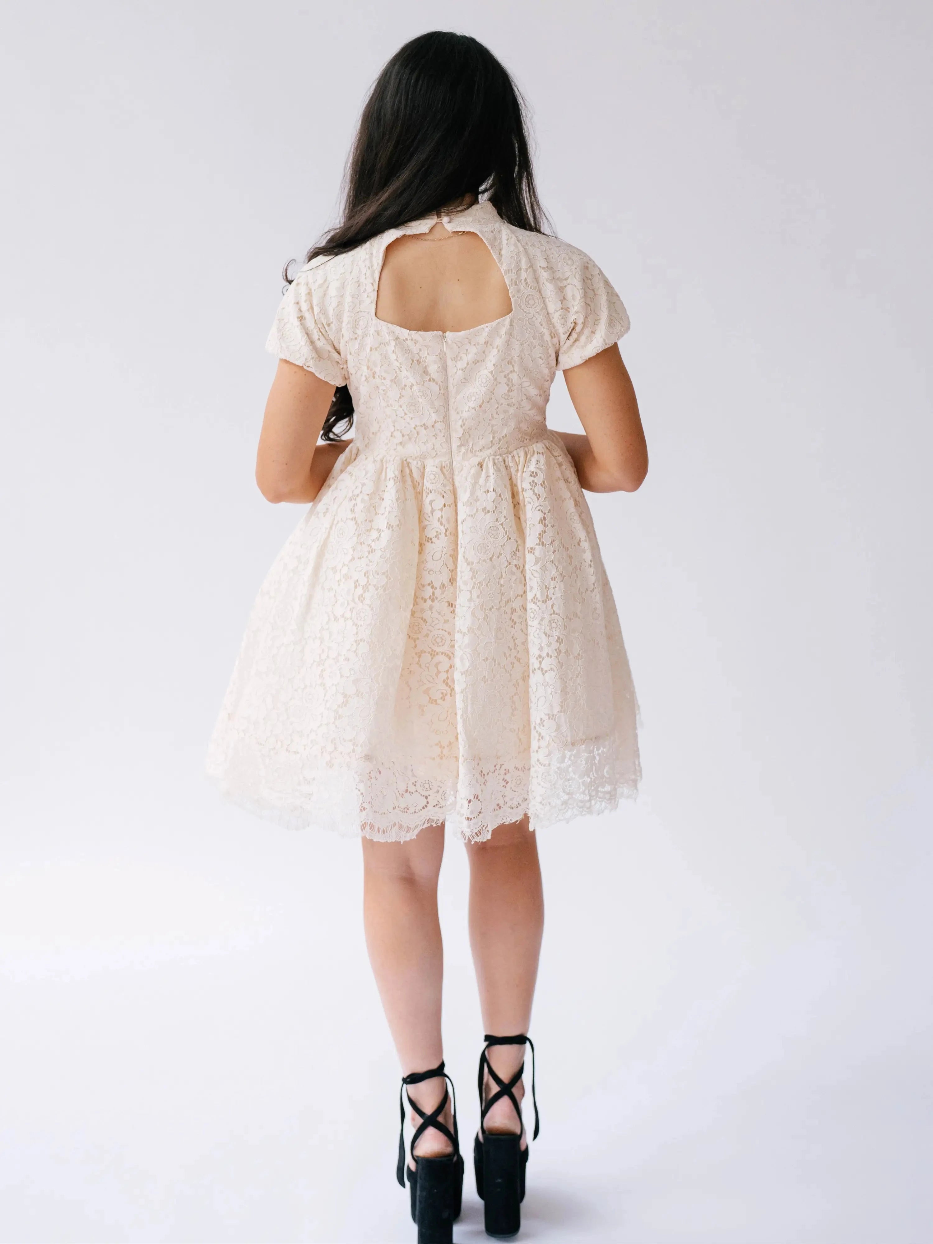 Rear view of The Victorian Lace Tea Party Mini Dress showing a back keyhole cutout and zipper closure in cream lace fabric.