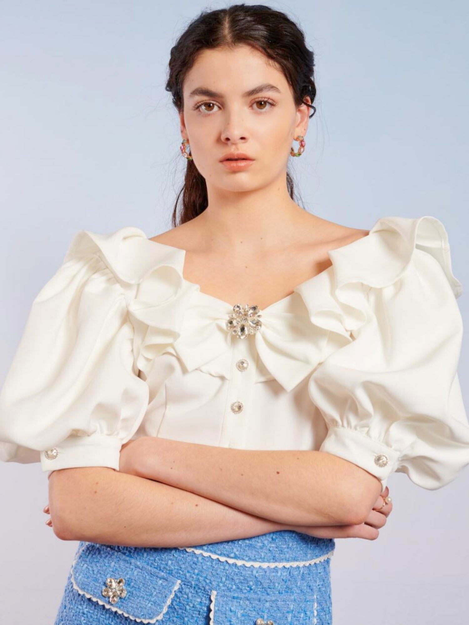 Woman in a white ruffled blouse and blue jeans wearing the Tide Jewel Crop Top Blouse