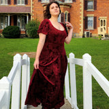 Woman in a long burgundy velvet dress on a white wooden bridge showcasing the Velvet Viola Dress