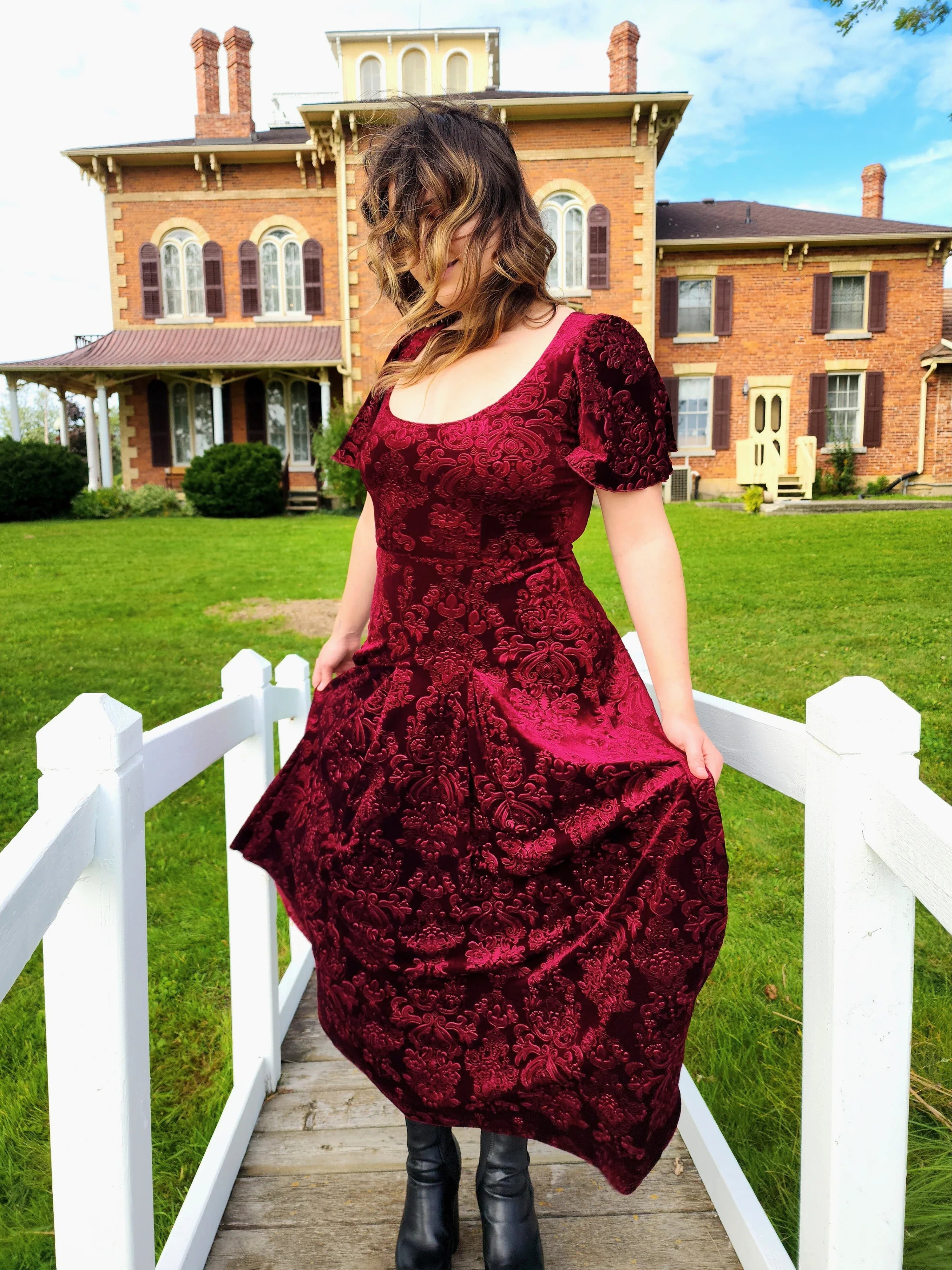 Woman in a burgundy velvet viola dress with short sleeves, showcasing elegance and style