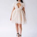 White lace mini dress with a keyhole cutout and short puffed sleeves paired with black platform sandals.