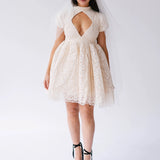 White lace mini dress with a keyhole cutout and short puffed sleeves paired with black platform sandals.