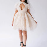 White lace mini dress with a keyhole neckline and short puffy sleeves paired with black platform heels.