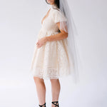 Short white lace mini dress with flutter sleeves paired with black platform heels and a long veil. Perfect for weddings