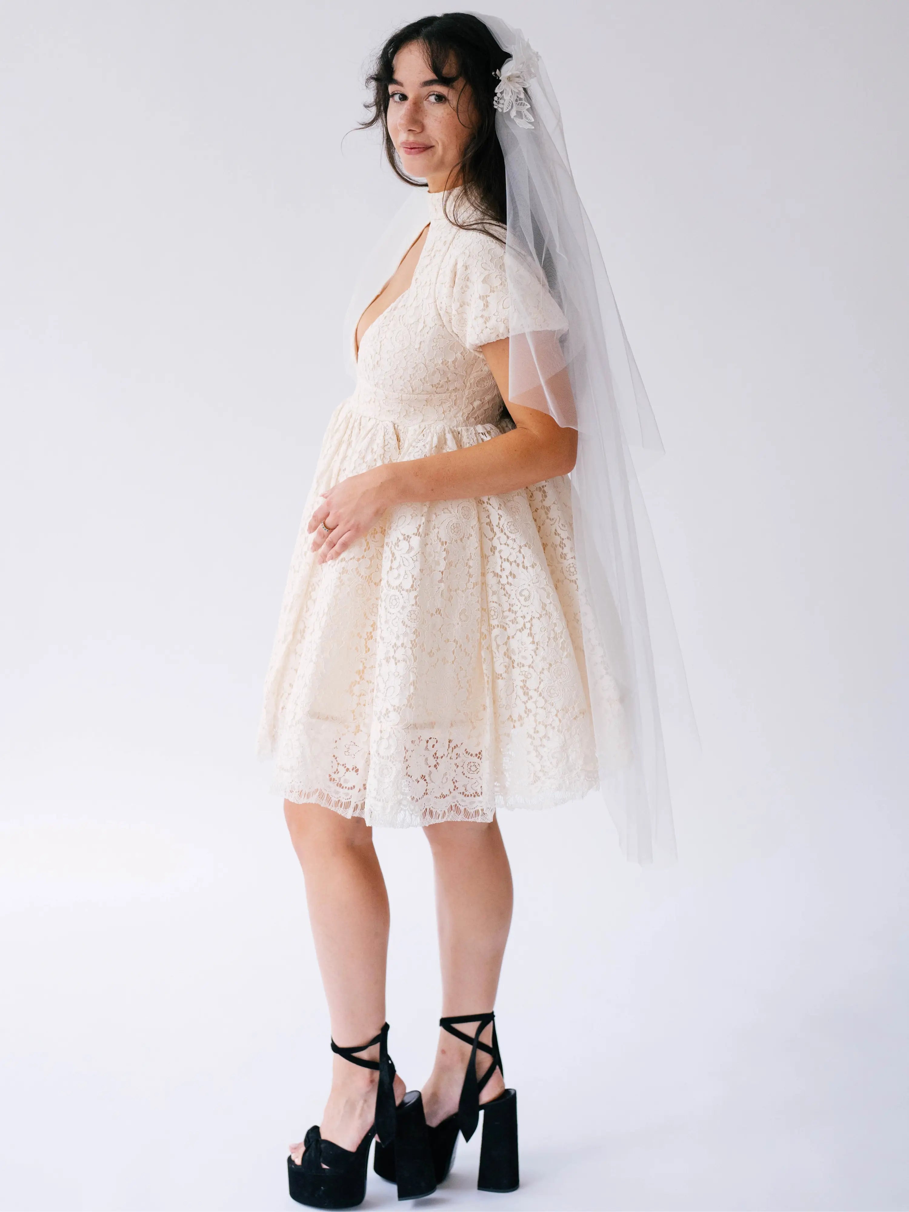 Short white lace mini dress with flutter sleeves paired with black platform heels and a long veil. Perfect for weddings