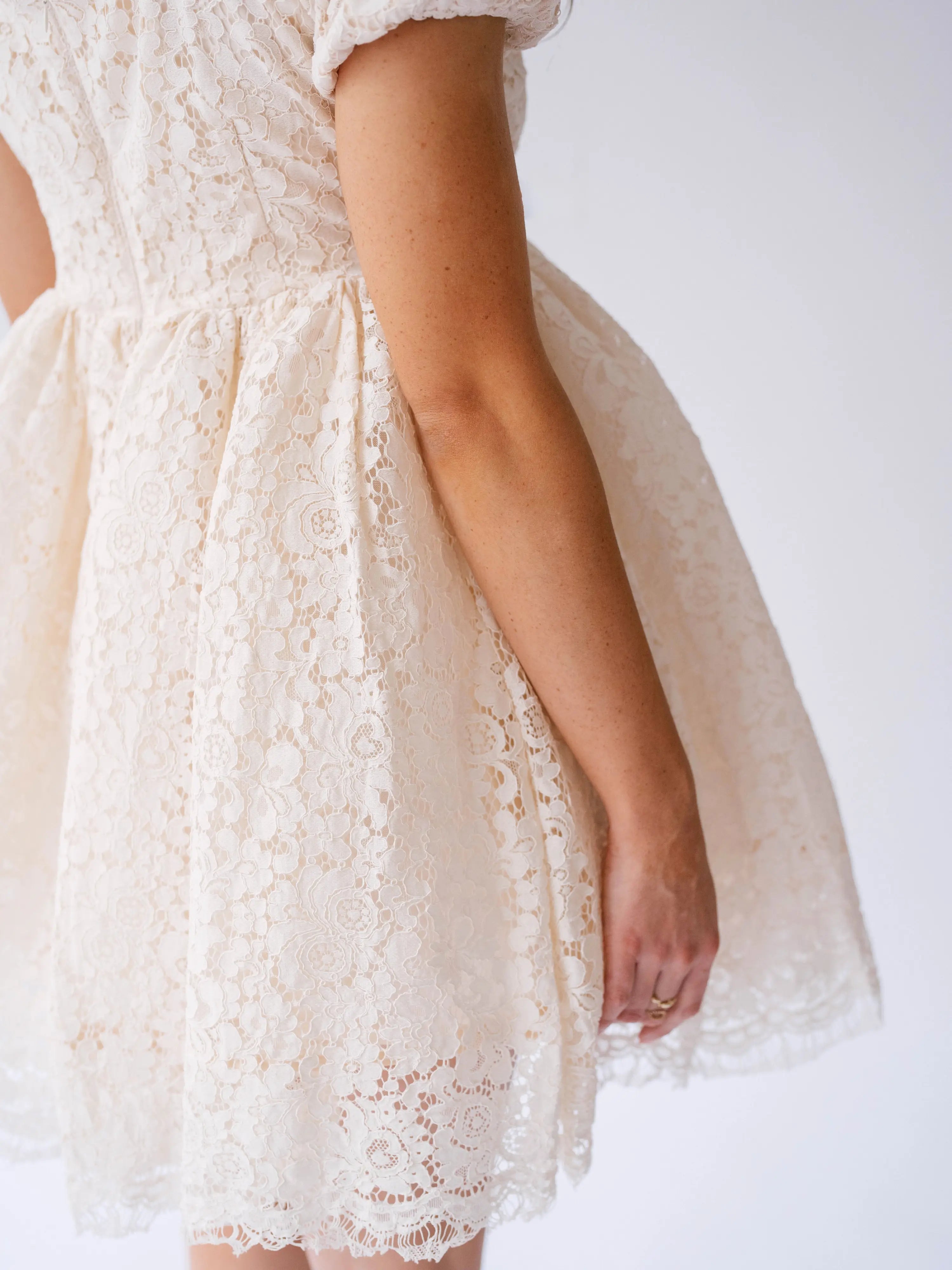 Delicate white lace mini dress with short sleeves and a flared skirt.