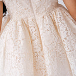 Elegant white lace mini dress with a full skirt and floral pattern. Perfect for weddings.