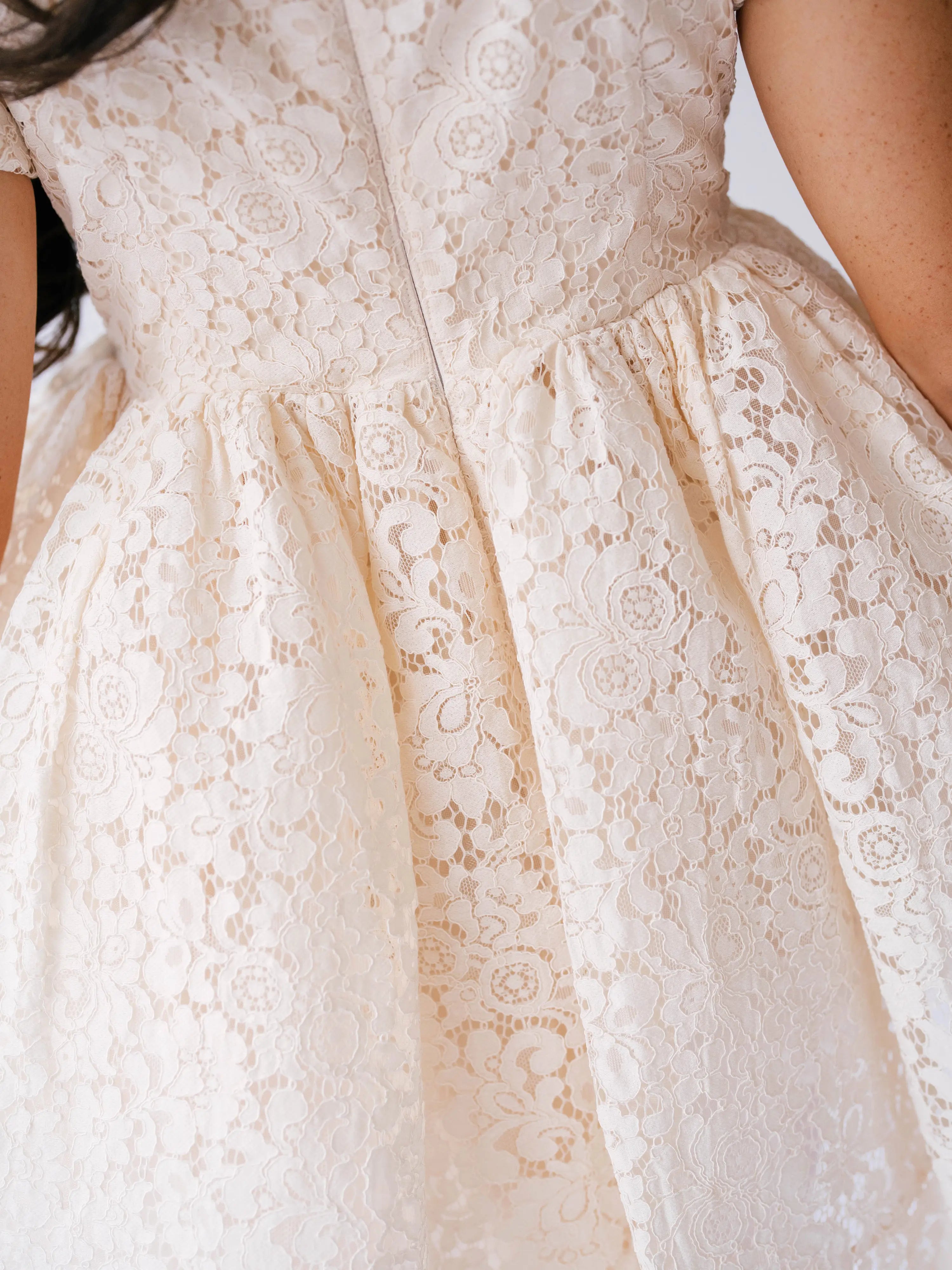 Elegant white lace mini dress with a full skirt and floral pattern. Perfect for weddings.