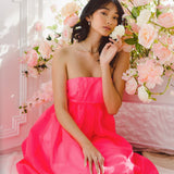 Woman in a pink strapless dress among flowers, showcasing Watermelon Sugar Ambrosia style