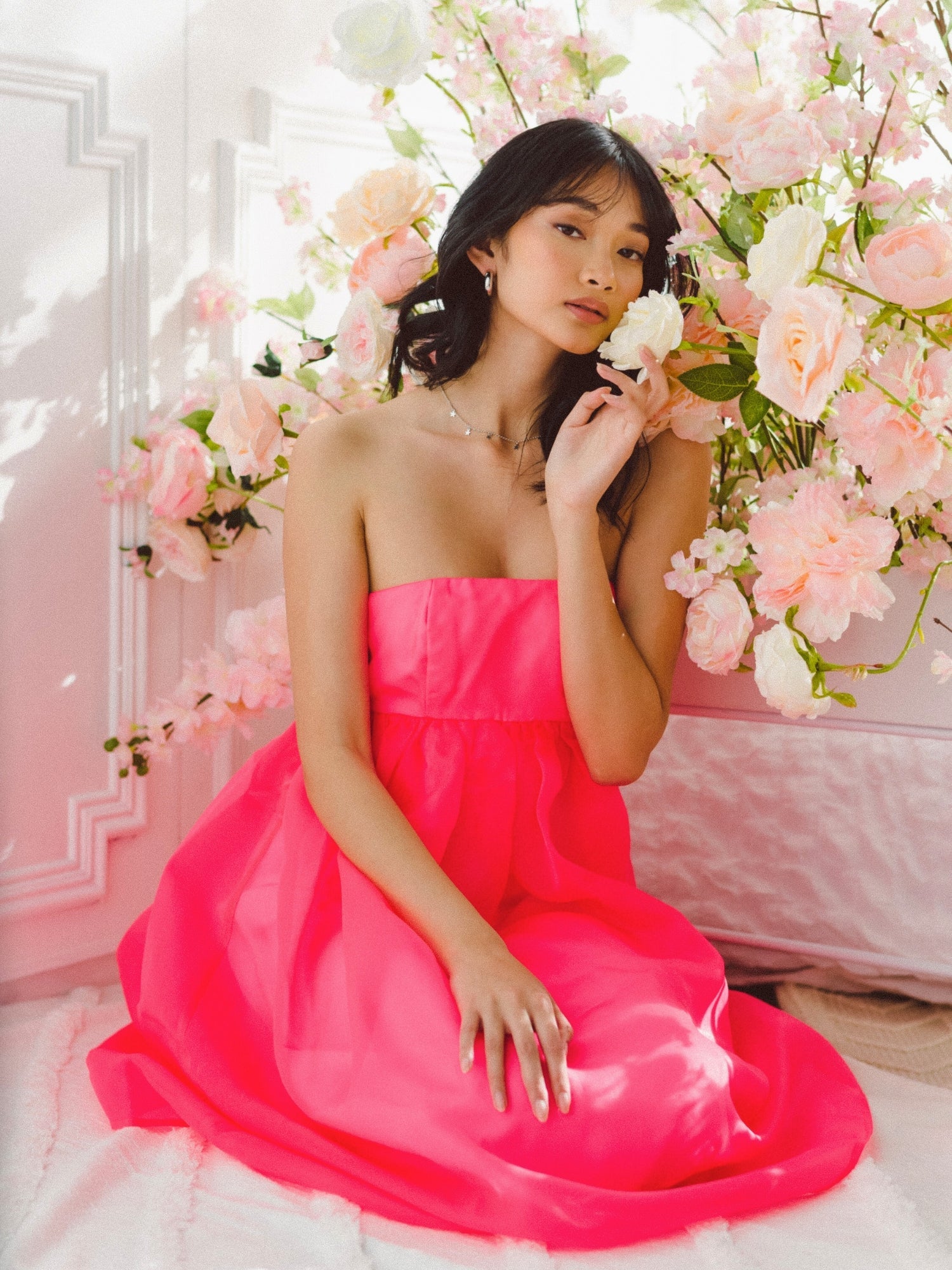 Woman in a pink strapless dress among flowers, showcasing Watermelon Sugar Ambrosia style