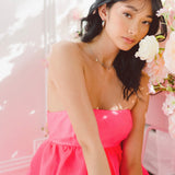 Young woman in Watermelon Sugar Ambrosia dress with white flowers backdrop