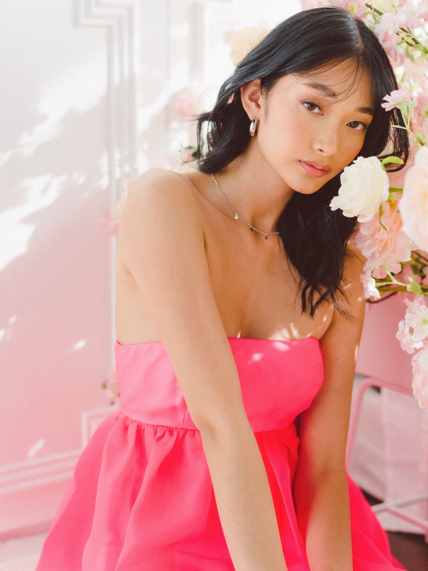 Young woman in Watermelon Sugar Ambrosia dress with white flowers backdrop