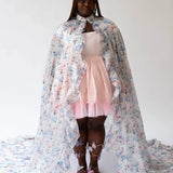 Young girl in a pink dress and floral cape featuring the Wild Bloom Priestess design