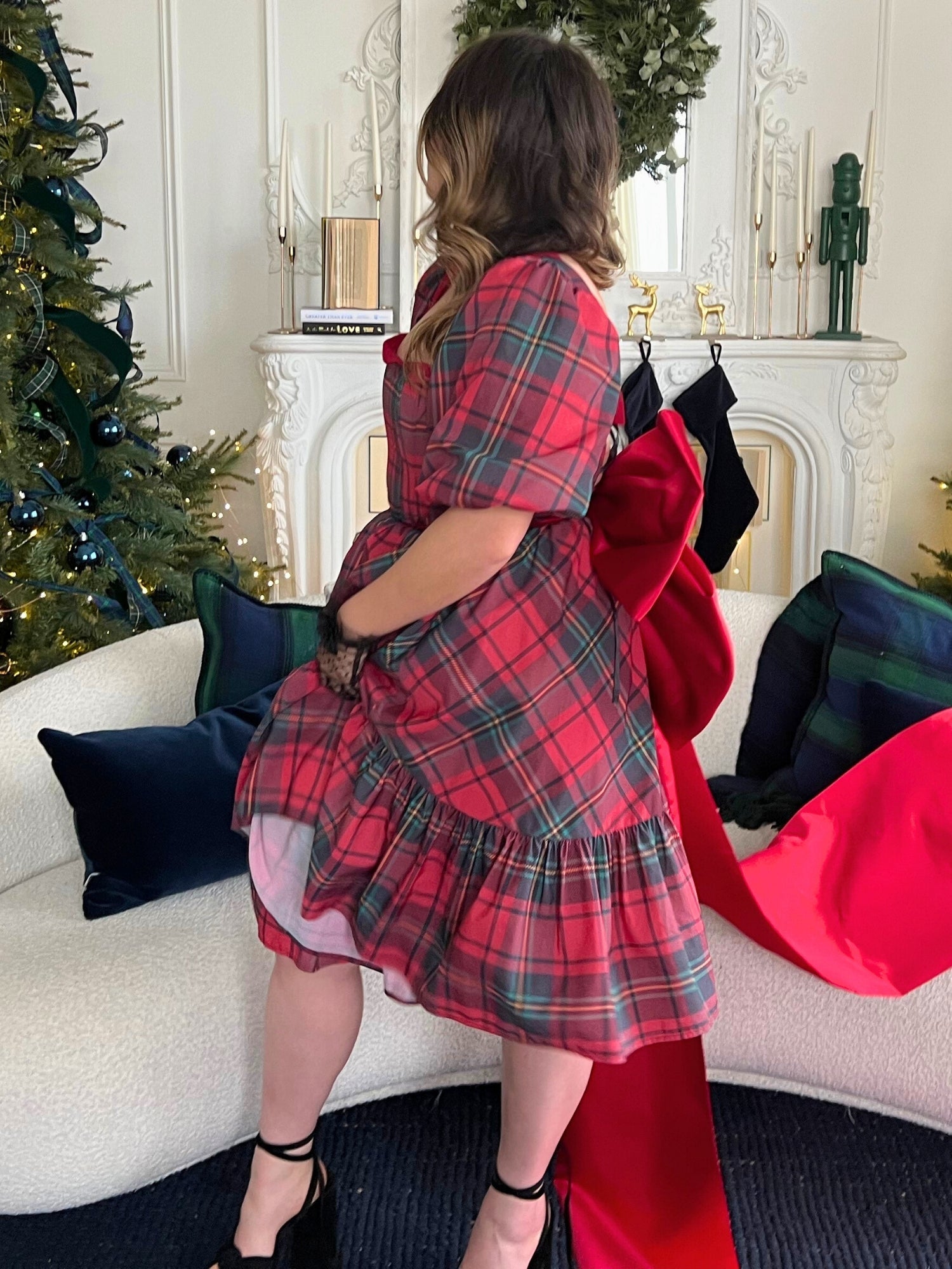 Woman in a Winter Tartan Josephine Midi Dress featuring a grand bow sash and ruffled hem