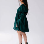 A woman wearing a green bell sleeve mini dress on a white background.
