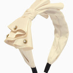 Cream-colored bow headband with decorative bow and rhinestone accents for elegant gowns